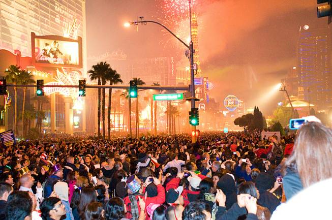 Crowds watch and react to the fireworks display above the Strip on New Year's Eve, Saturday, Dec. 31, 2011.