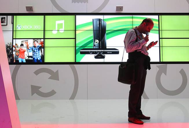 A man checks messages on his smartphone in the Microsoft booth during the 2012 International Consumer Electronics Show (CES) in Las Vegas, Nevada, Jan. 11, 2012. CES, the world's largest consumer technology tradeshow, runs through Friday.