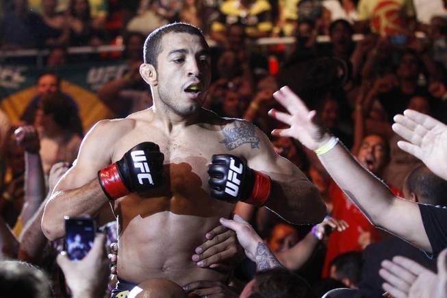 Defending featherweight champion Jose Aldo, from Brazil, celebrates with fans after defeating Chad Mendes, from the US, in the first round during their featherweight title bout at UFC 142 in Rio de Janeiro, Brazil, Sunday Jan. 15, 2012.