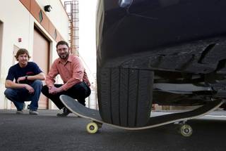 Ross Graham, left, and Clinton Anderson pose as a car rests on one of their skateboards at the Colonial Brand skateboard company manufacturing facility in Las Vegas Thursday, Jan. 26, 2012. The start-up company is planning to market their hand-made skateboards as the world's strongest.