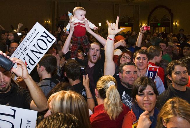A man holds up a baby as Republican presidential candidate Rep. Ron Paul, R-Texas, leaves the stage after speaking at a rally at the Green Valley Ranch Resort in Henderson on Tuesday, Jan. 31, 2012.
