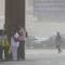 Photo: Pedestrians take cover behind a pole as high winds