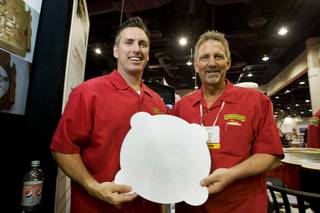 Jeff Pugh, left, Perfect Crust CEO, and Tom Esterley, vice president of sales and marketing, pose with the Perfect Crust Pizza Liner during the International Pizza Expo at the Las Vegas Convention Center Wednesday, March 14, 2012. The special paper liner absorbs excess oil and is embossed to keep the crust slightly elevated over the paper, keeping the crust crisp in the delivery box.
