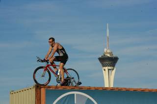 Spencer Larson rides his bicycle on top of storage containers along the I-15 during rush hour to promote exercise, Tuesday March 20, 2012.