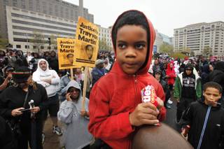 Isaiah Henry-Simpson, 7, of Arlington, Va., eats Skittles candy while attending a rally with his parents in support of Trayvon Martin at Freedom Plaza in Washington, on Saturday, March 24, 2012. Many people in attendance brought candy, ice tea, and wore hooded sweatshirts, or hoodies, in support of the unarmed young black teen, who was fatally shot by a volunteer neighborhood watchman. 