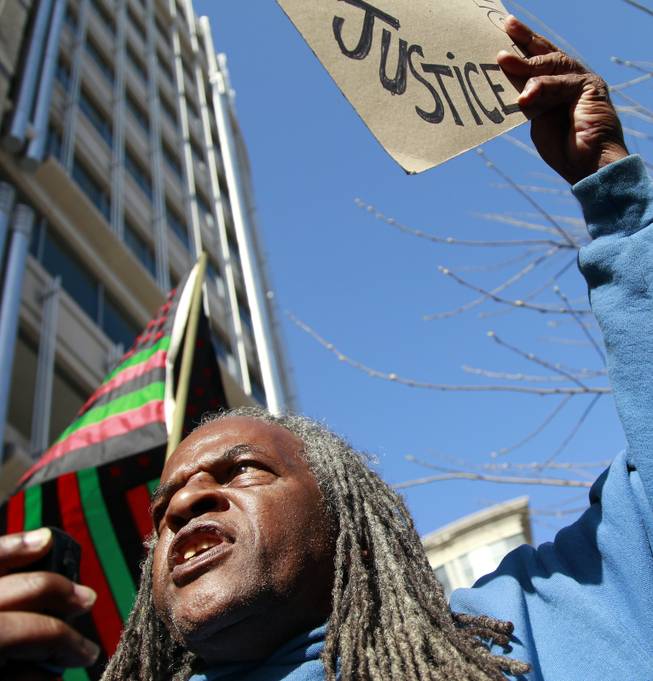 Yango Sawyer, right, joins a crowd to rally in front of a Department of Justice office, calling on justice for Trayvon Martin, Monday, March 26, 2012, in Washington. 