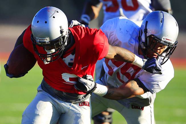 UNLV's Eric Johnson tries to escape defensive back Tajh Hasson during the Rebels spring football game Friday, April 20, 2012.
