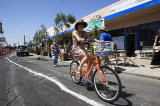 A bike rider rides past the shops during the Greener Block event on Main Street at Charleston Boulevard Saturday, April 28, 2012.