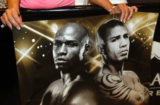 A fan holds a poster featuring Floyd Mayweather Jr., left, and WBA super welterweight champion Miguel Cotto during official arrivals in the lobby of  the MGM Grand Tuesday, May 1, 2012. Mayweather  will challenge Cotto of Puerto Rico at the MGM Grand Garden Arena on Saturday. STEVE MARCUS