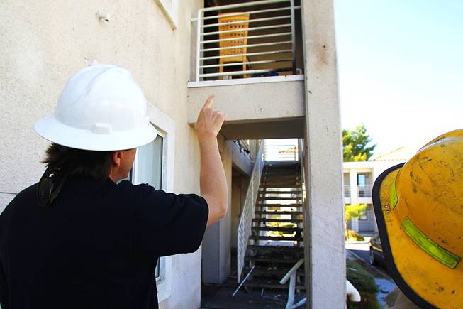 A fire investigator points to an area that has a different burn pattern and evidence of stucco under high heat, the reddish-brown discoloration near the railing, at the scene of an apartment fire Friday, May 4, 2012.