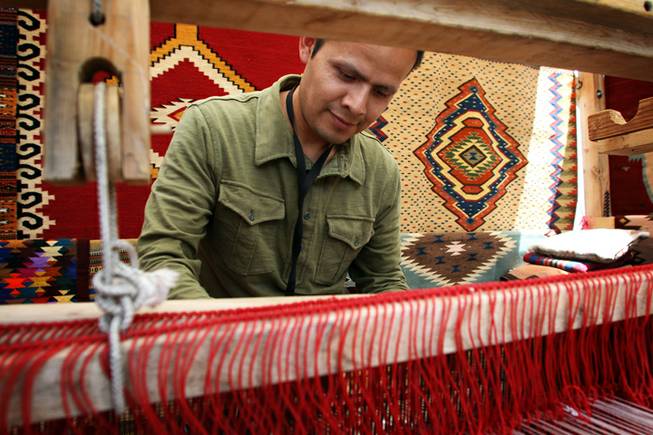 Antonio Mendoza, 38, of Orange County, Calif., demonstrates on a loom how he weaves his handmade tapestries, blankets and other products. Mendoza said he focuses on collectors more now than before the recession because they are the ones who are "not afraid to spend" on art these days.