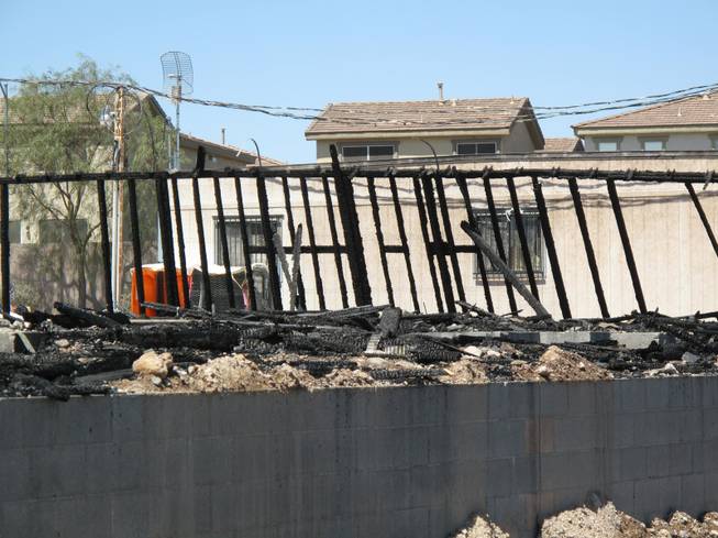 Two melted portable restroom facilities next to an office trailor are seen behind scorched wood on the location at an apartment construction site. Fire crews responded to an early morning fire at 1131 Wigwam, the future site of Theory Apartments on Wednesday , June 20, 2012.
