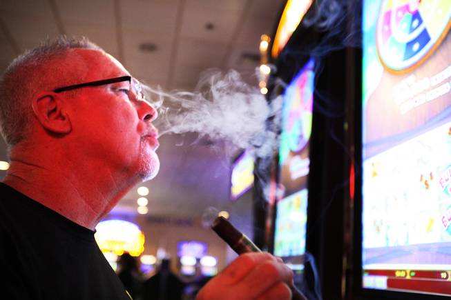 Tom Devenish smokes a cigar while playing the slots at the Eldorado Casino in downtown Henderson on Friday, June 22, 2012.