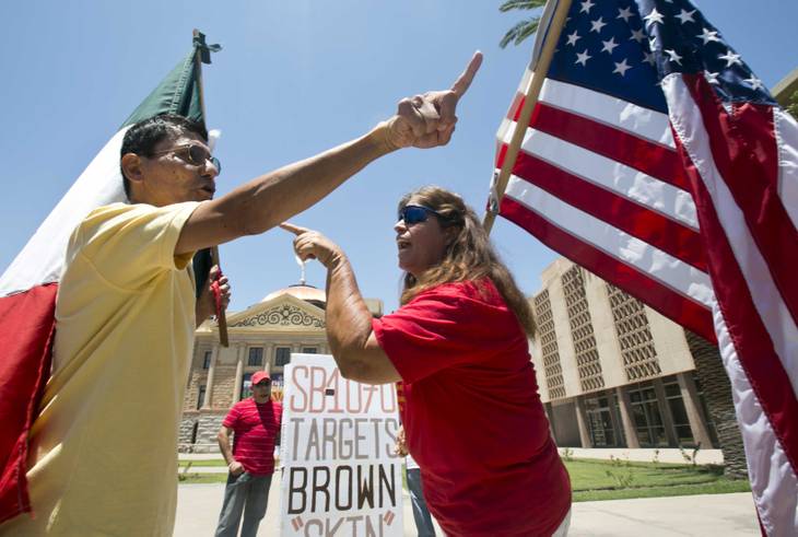 Andy Hernandez, carrying a Mexican flag, and Allison Culver, carrying an American flag argue over the controversial Arizona immigration law outside the State Capitol Building in Phoenix. 