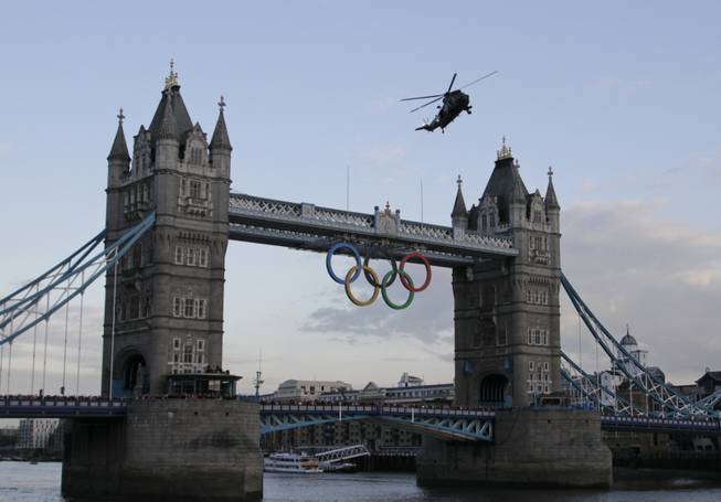 A British Royal Marine Sea King helicopter carrying the Olympic flame flies past the Tower Bridge in London, as it arrives to the Tower of London, Friday, July 20, 2012. The Olympic Torch arrived in London after it was carried around England in a relay of torchbearers to make its way to the London 2012 Olympic Games opening ceremony on July 27, 2012. (AP Photo/Lefteris Pitarakis)