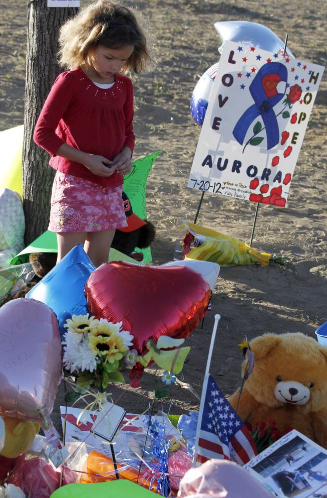Serenity Brydon, 7, from Aurora, Colo., looks at a memorial near the the Century 16 movie theater Sunday, July 22, 2012, where 12 people were killed and dozens were injured in a shooting attack early Friday.