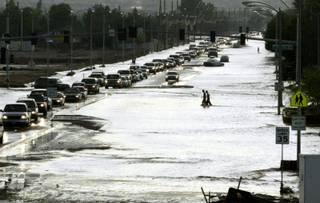 Pedestrians wade across Craig Road near U.S. 95  after a powerful thunderstorm dumped three inches of rain in about 90 minutes in the northwest section of the city Wednesday, August 19, 2003. The torrential downpour caused flash flooding that swamped neighborhoods and trapped people in their cars.