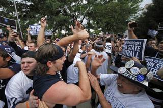 Penn State University linebacker Michael Mauti, second from left foreground, and his teammates are greeted by a pep rally of supporters on the way to a morning workout outside the Lasch Football building on the Penn State main campus in State College, Pa., Tuesday, July 31, 2012. 