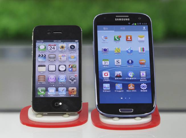 Apple's iPhone 4S, left, and Samsung Electronics' Galaxy S III are displayed at a mobile phone shop in Seoul, South Korea, on Friday, Aug. 24, 2012. 