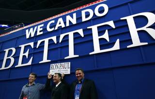 Nevada delegate and former state Ron Paul campaign chair Carl Bunce, right, and Nevada delegate David Isbell, center, help hold up a Ron Paul sign under Mitt Romney's 