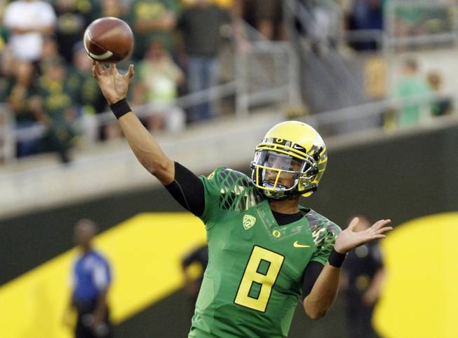 Oregon quarterback Marcus Mariota passes the ball downfield in the first half of a game against Arkansas State. Oregon went on to 57-34.