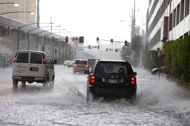 Cars drive through storm runoff behind Planet Hollywood during a rainstorm Tuesday, Sept. 11, 2012.  