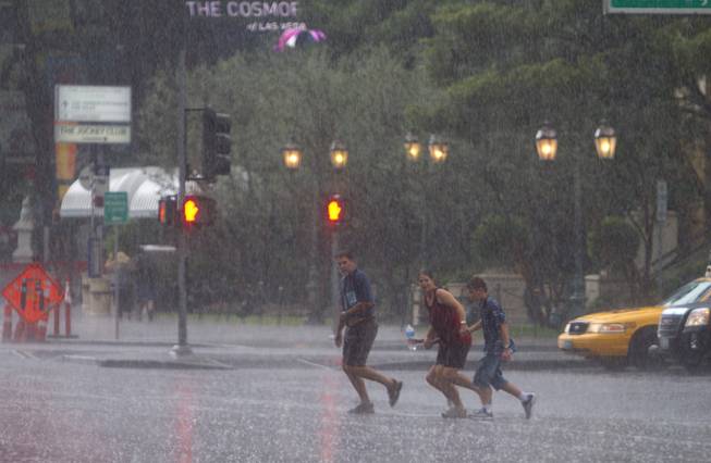 A family crosses Las Vegas Boulevard in front of the Bellagio during a rainstorm Tuesday, Sept. 11, 2012.