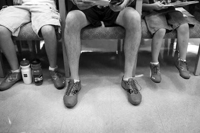 Arturo Martinez-Sanchez, center, sits in the Valley Hospital waiting room with his sons Cristopher, left, 10, and Alejandro, 5, all in matching shoes on the day of Arturo's brain surgery Sept. 12, 2012.