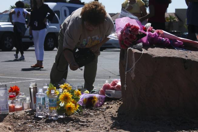 Cecilia Mendez, co-worker of one of the victims, lights a candle at the memorial site of the bus stop crash Friday, Sept. 14, 2012.