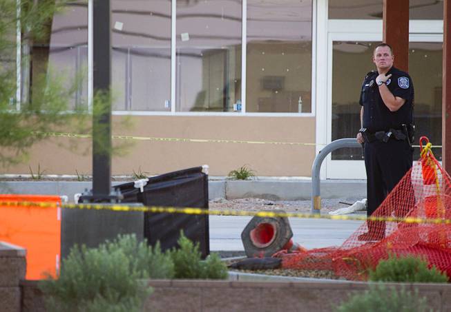 A North Las Vegas Police officer stands near a man's body at the scene of a fatal officer-involved shooting at Martin Luther King Jr. Boulevard and Cheyenne Avenue in North Las Vegas Wednesday, Sept. 19, 2012. The man's body is behind orange and black screens at left.