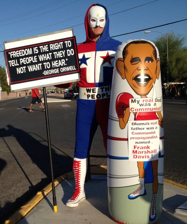 Richard McCaslin, who goes by “The Phantom Patriot” when in costume, protests at a rally for President Barack Obama on Sunday at Desert Pines High School.