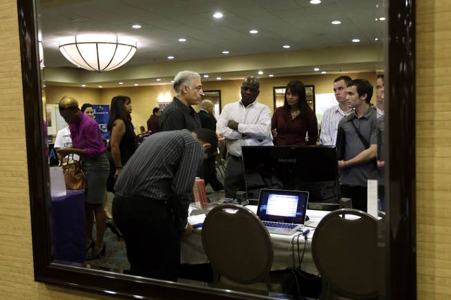 In this Monday, Sept 17, 2012, file photo, Robert Orkin of the company TxT-Alert, third from left, talks with job seekers during a job fair held by National Career Fairs in Fort Lauderdale, Fla. The U.S. unemployment rate fell to 7.8 percent last month, dropping below 8 percent for the first time in nearly four years.