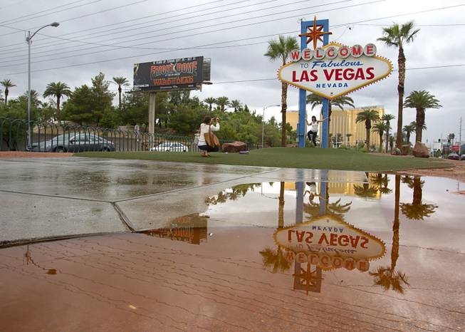 The "Welcome to Las Vegas"  sign is reflected in a rain puddle as Amanda Thompson photographs her sister Melinda Casey Thursday, Oct. 11, 2012. Thompson is living in England and Casey is from Australia so they decided to meet halfway for a Vegas vacation, they said. 