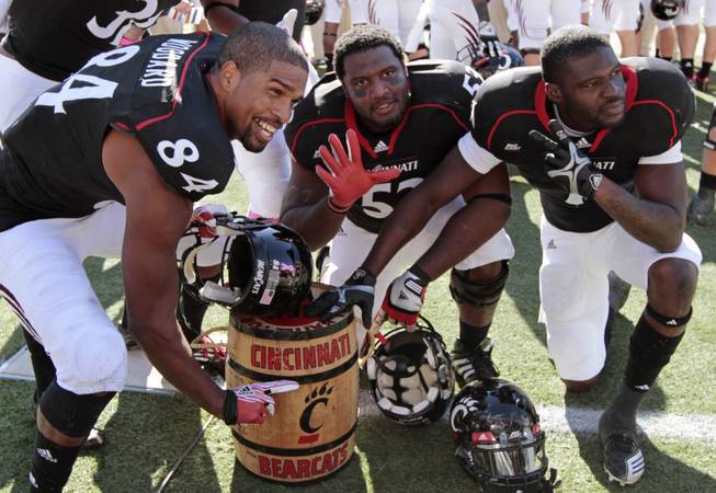 Cincinnati players Orion Woodard (84), Randy Martinez, center, and Kenbrell Thompkins celebrate with the Keg of Nails trophy in the closing seconds of their 25-16 win over Louisville in an NCAA college football game, Saturday, Oct. 15, 2011, in Cincinnati. Cincinnati has won five straight games in the rivalry that dates back to 1929.