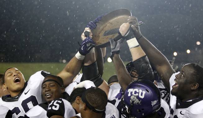 Members of the TCU football team reach in to touch the "Iron Skillet," their prize for beating SMU in an NCAA college football game on Saturday, Sept. 29, 2012, in Dallas. TCU won 24-16. 