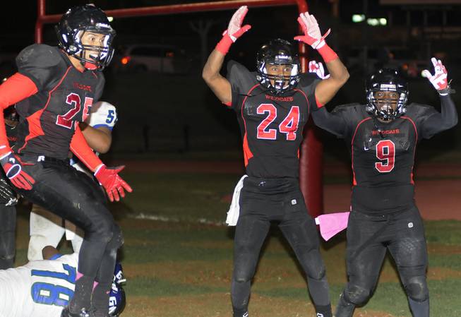 Wildcat defensive players Angel Perez (25), Chritian Slack (24), and D'Anthony Wade (9) celebrate as they signal touchdown after Las Vegas recovered a Green Valley fumble for a defensive score during the first half of play at Las Vegas High on Friday night.