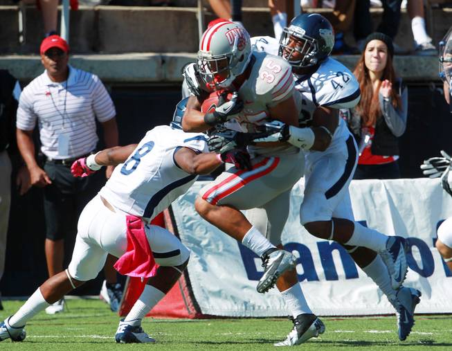 UNLV running back Tim Cornett gets taken down by UNR defensive back Marlon Johnson, left, and linebacker DeAndre Boughton during their game Saturday, Oct. 13, 2012 at Sam Boyd Stadium. UNR came from behind and won the game, for the eighth consecutive time, 42-37.