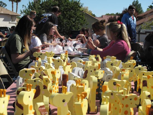 A group of teenagers paint and assemble wooden toy giraffes and elephants among other animals that will then be donated to charity as part of their Church of Jesus Christ of Latter-day Saints Day of Service community project on Saturday. 