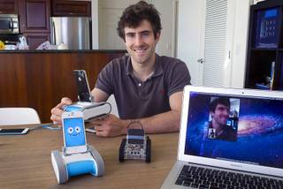 Keller Rinaudo, one of the three Romotive founders, poses  with the new Romo smartphone robot at the Romotive offices in downtown Las Vegas Wednesday, Oct. 24, 2012.  The original model is at center. The new Romo can be controlled over the Internet. Rinaudo's face, captured by the Romo in his hands, is shown on the computer screen at right. The new Romo with enhanced features can be ordered on kickstarter.com and is featured in the Neiman Marcus Holiday catalog.