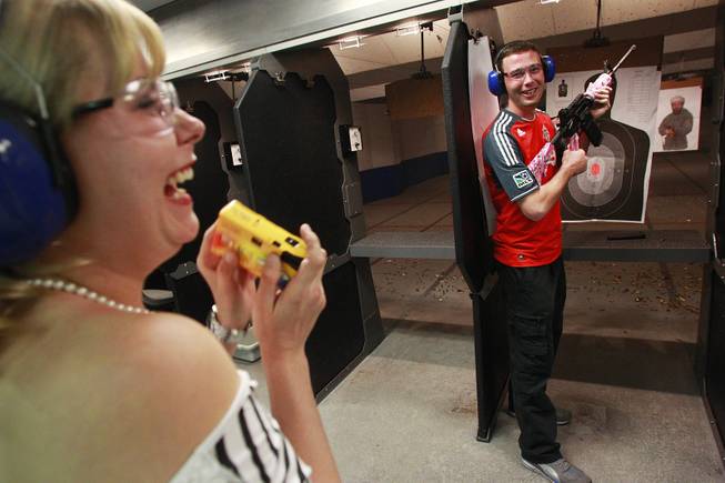 Roxie Jekosz laughs while her boyfriend Matthew Cook poses with a machine gun at the Guns and Ammo Garage Oct. 25, 2012.