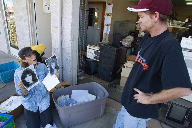 Singer Randy Williams shows photos of Deborah Thompkins to Ken Barry as he recovers items from an auction lot of items that Barry had purchased Thursday, Oct. 25, 2012.