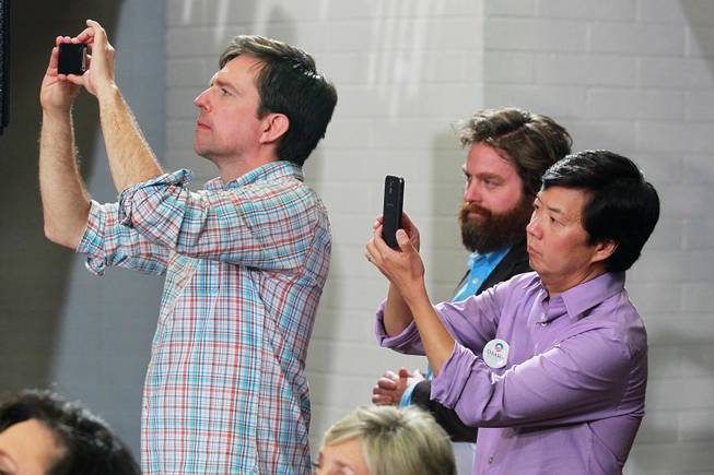 Actors Ed Helms, left, and Ken Jeong take cell phone photos while watching first lady Michelle Obama with fellow actor Zach Galifianakis at a campaign appearance for President Barack Obama, at Orr Middle School Friday, Oct. 26, 2012.