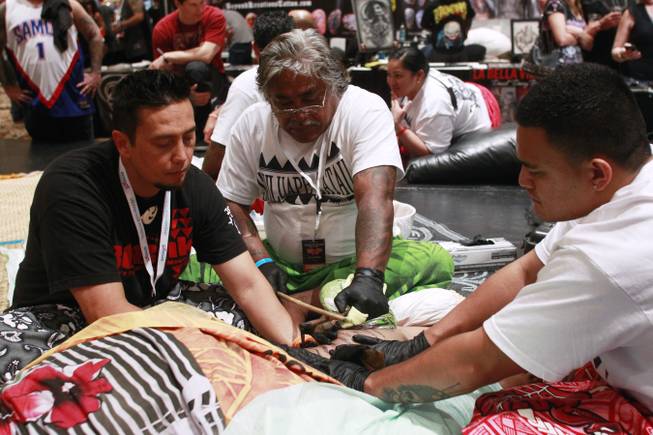 Master Tattooist Tufuga Su'a Alaiva'a Petelo Sulu'ape works on a woman's leg with traditional Samoan tattoo tools at while being assisted by Lane Wilcken, left, and Fesolai Imo Levi Mario Barth's Biggest Tattoo Show On Earth at the Mirage Saturday, Oct. 27, 2012.