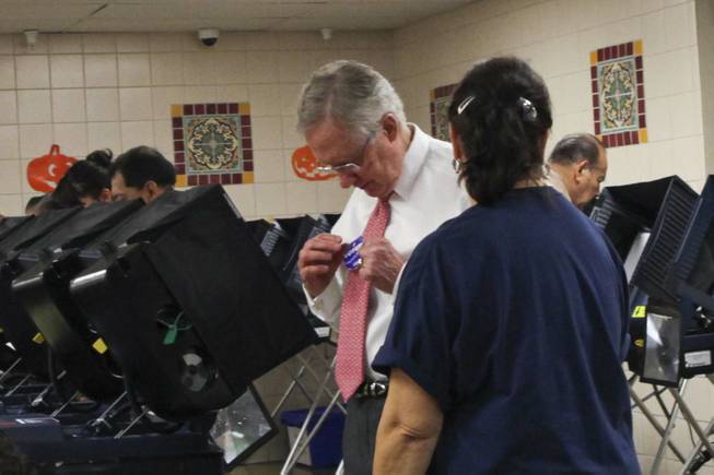 Sen. Harry Reid affixes an I voted sticker to his tie after casting an early vote at the Cardenas Market on East Bonanza polling station in Las Vegas on Wednesday, Oct. 31, 2012.