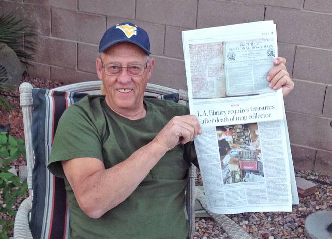 John Feathers holds a Los Angeles Times story printed in the Las Vegas Sun about his son, John E. Feathers, and his map collection. 