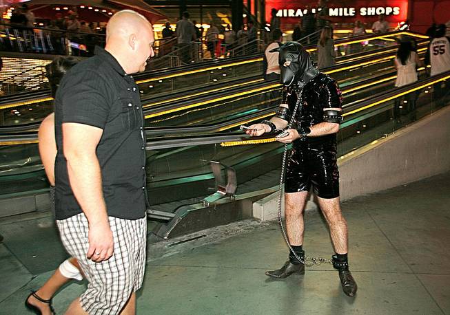 Adam Benson, of Leeds, England, wears a leather bondage suit and passes out handbiller cards on the Strip as part of a Halloween dare for his bachelor party, Oct. 31, 2012. 
