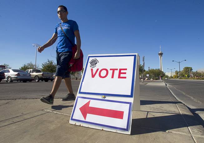 A man walks past a sign directing voters to a polling location at Fremont Middle School gym Tuesday, November 6, 2012.