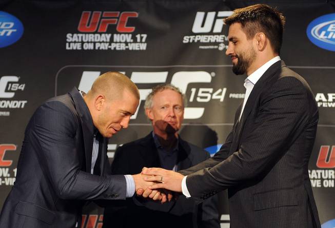 Defending UFC welterweight champion Georges St-Pierre, left, shakes hands with interim champion Carlos Condit, as president of UFC Canada Tom Wright, looks on following a news conference in Montreal, Thursday, Sept. 27, 2012, where they announced their upcoming UFC 154 fight which will take place in Montreal on Nov. 17.