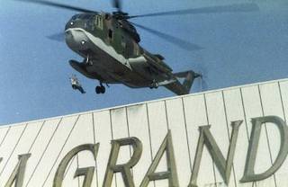 A person is seen hanging from a military helicopter as it flies over the MGM Grand sign during the Nov. 21, 1980, fire.