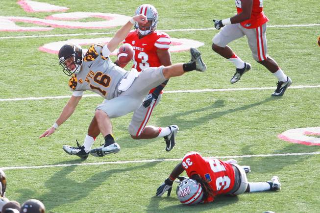 Wyoming quarterback Brett Smith gets upended by UNLV defensive back Sidney Hodge during the first half of their game Saturday, Nov. 17, 2012 at Sam Boyd Stadium.